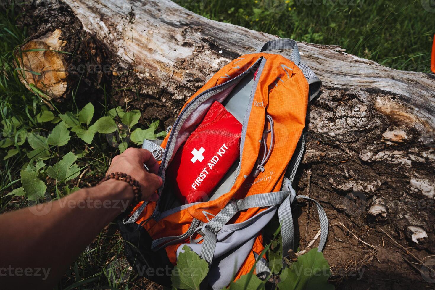 A first aid kit is in a backpack, a tourist in the forest takes a first aid kit out of his bag, safety in nature. photo