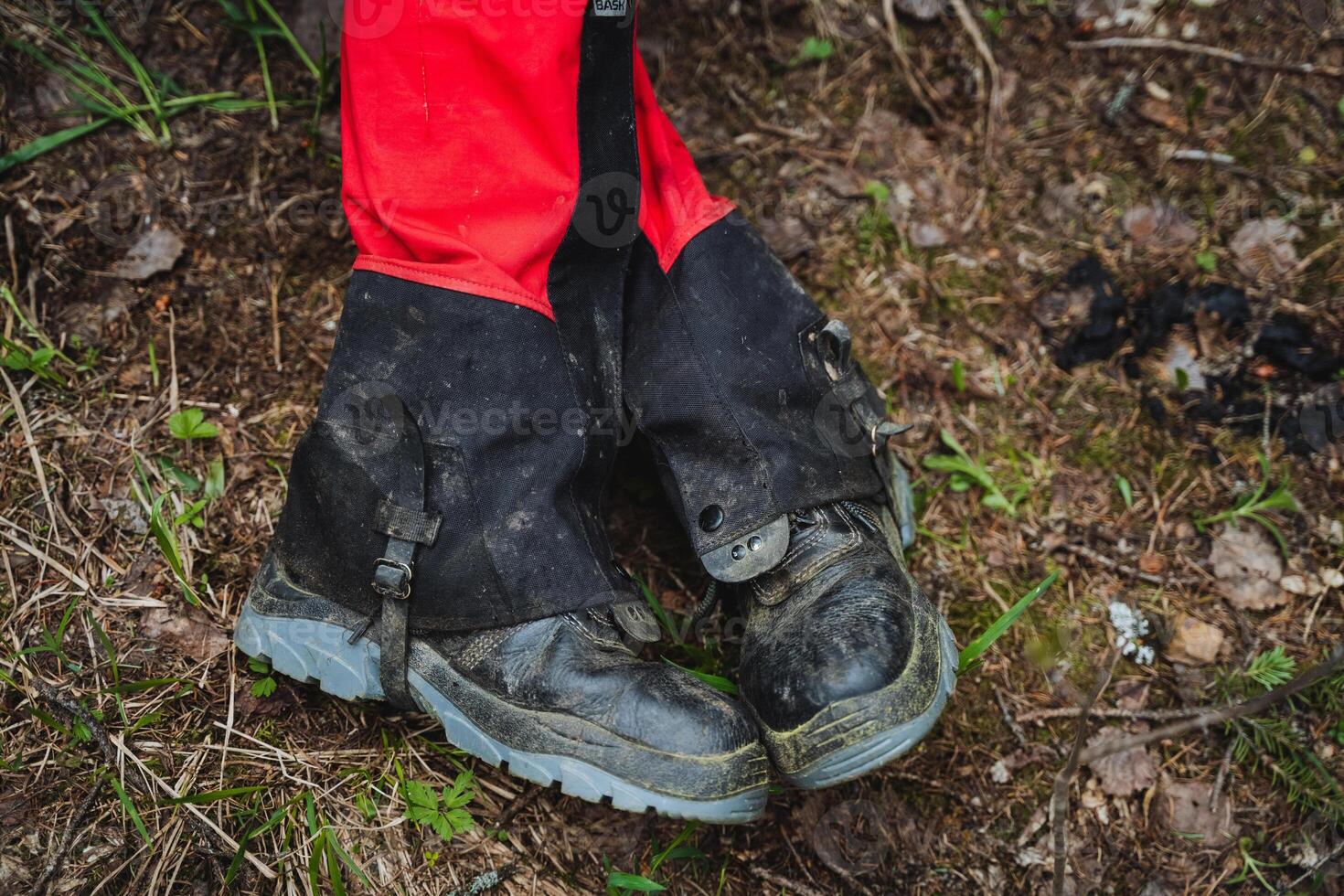 Person in red shorts and black gaiters stands on soil photo