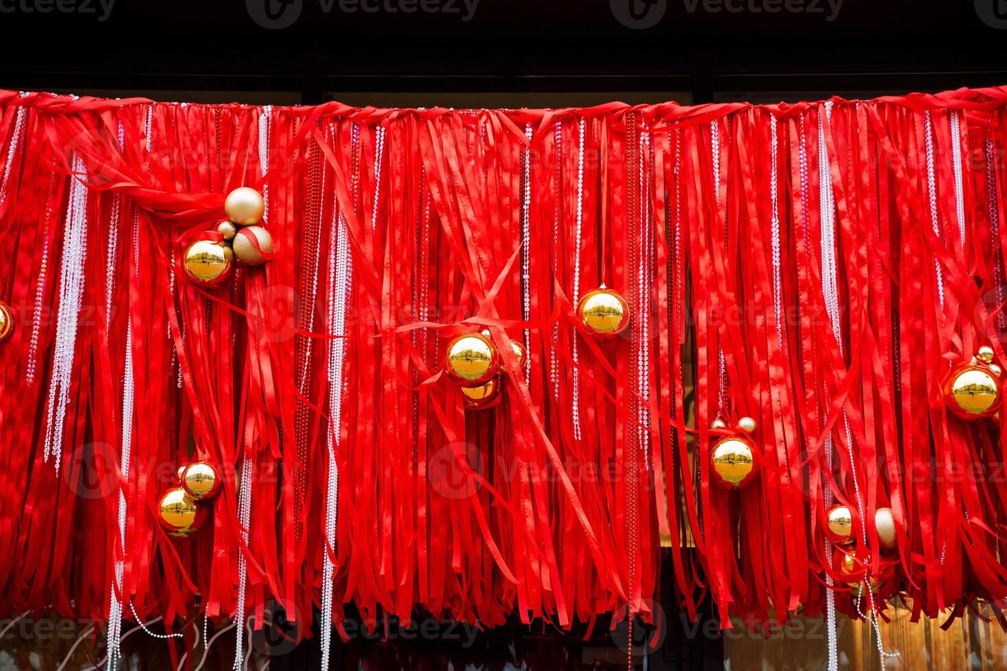 A beautiful row of vibrant red ribbons adorned with shimmering gold balls elegantly hanging from them, creating a visually stunning display that captures the essence of celebration photo