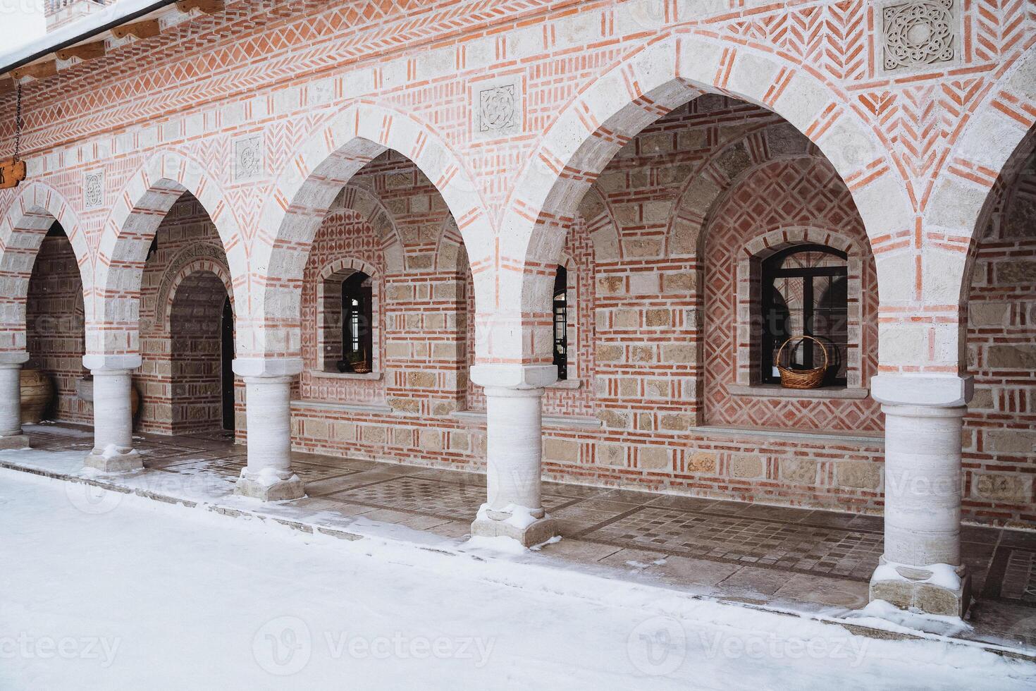 Snowcovered brick building featuring arches and columns photo
