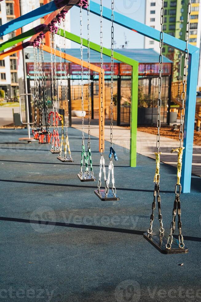 There is a vibrant row of colorful swings located in a beautifully designed park, inviting children and families to enjoy outdoor leisure and recreation activities together photo