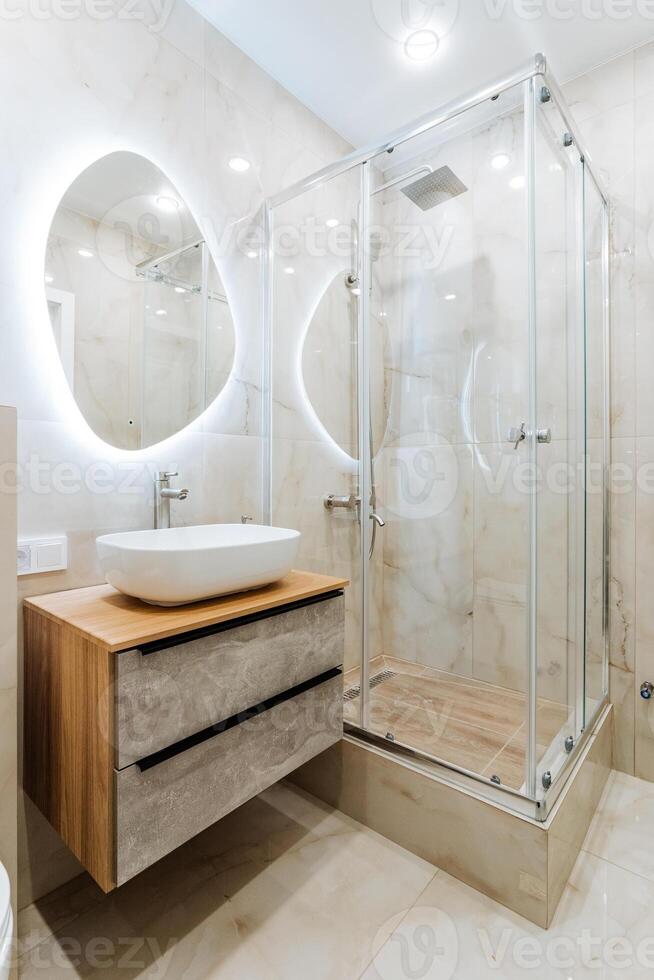 Modern bathroom with sink, mirror, and shower stall in a rectangular building photo