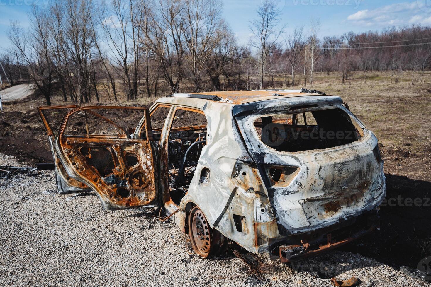 The car after the accident is in an open field outside the city, a burnt car, a rusty piece of metal, a disaster on the road. photo
