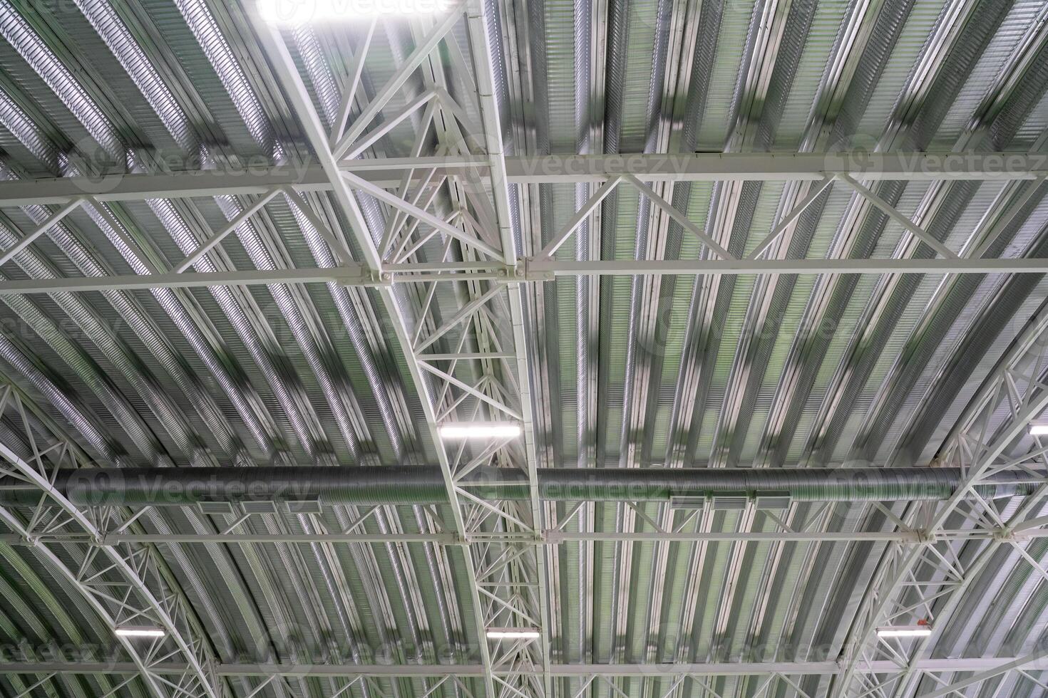 The ceiling of a large, spacious building features an intricate design with numerous metal beams that create a distinctive visual pattern, adding to the overall architectural beauty photo