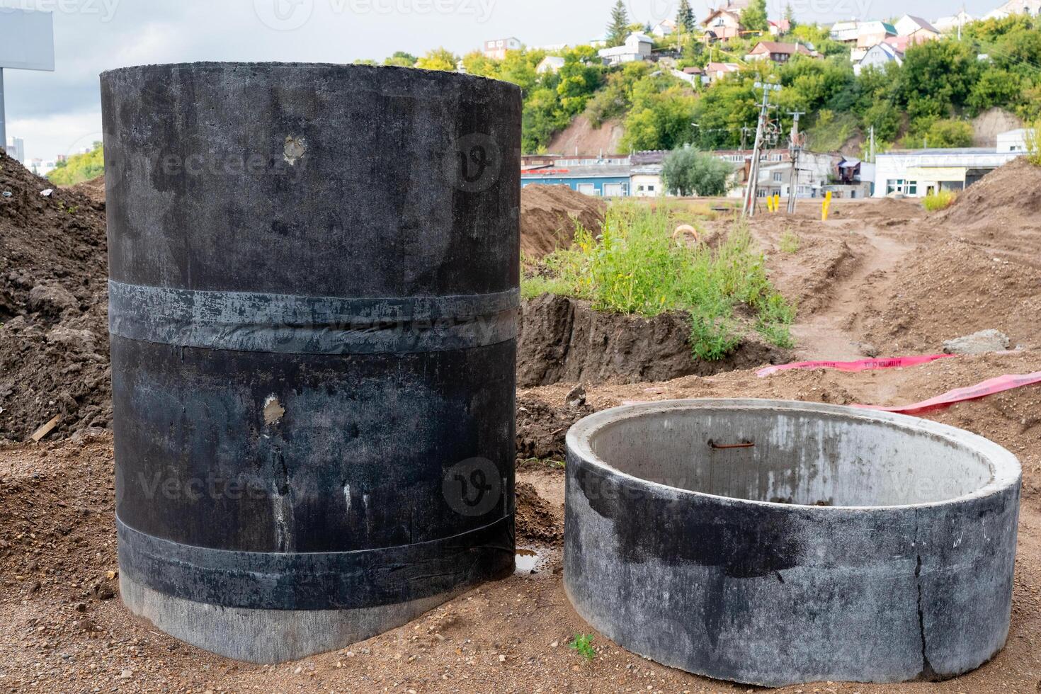 A bustling construction site featuring large concrete pipes with an expansive urban background visible nearby photo