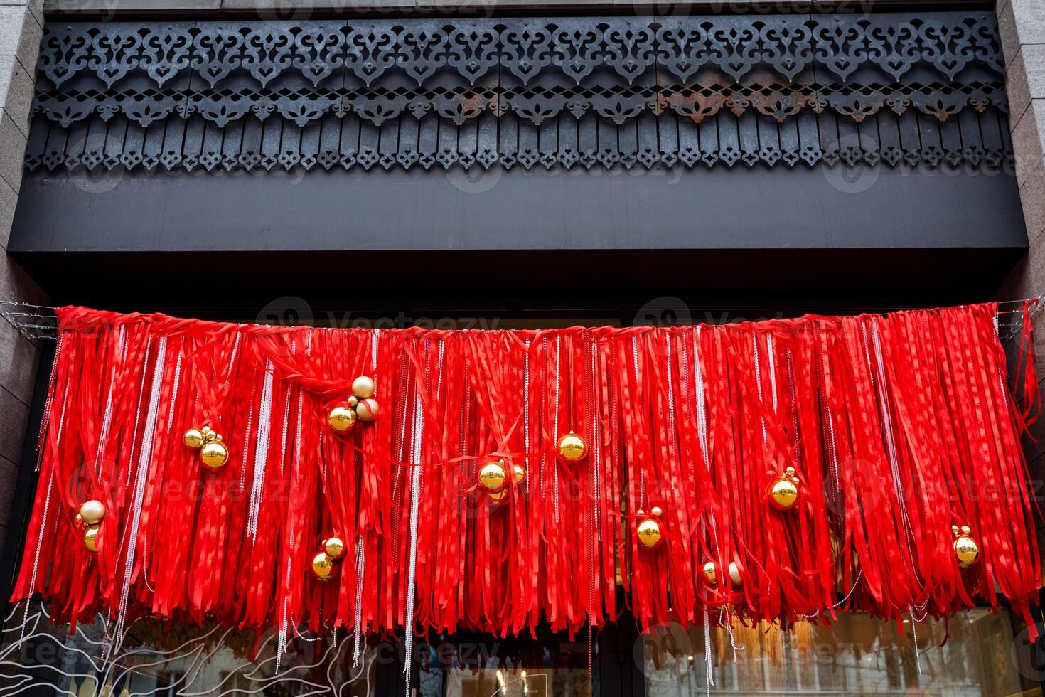 A beautifully designed store front that is adorned and decorated for the festive Christmas season, featuring lovely red ribbons and shiny gold ornaments that enhance its charm photo