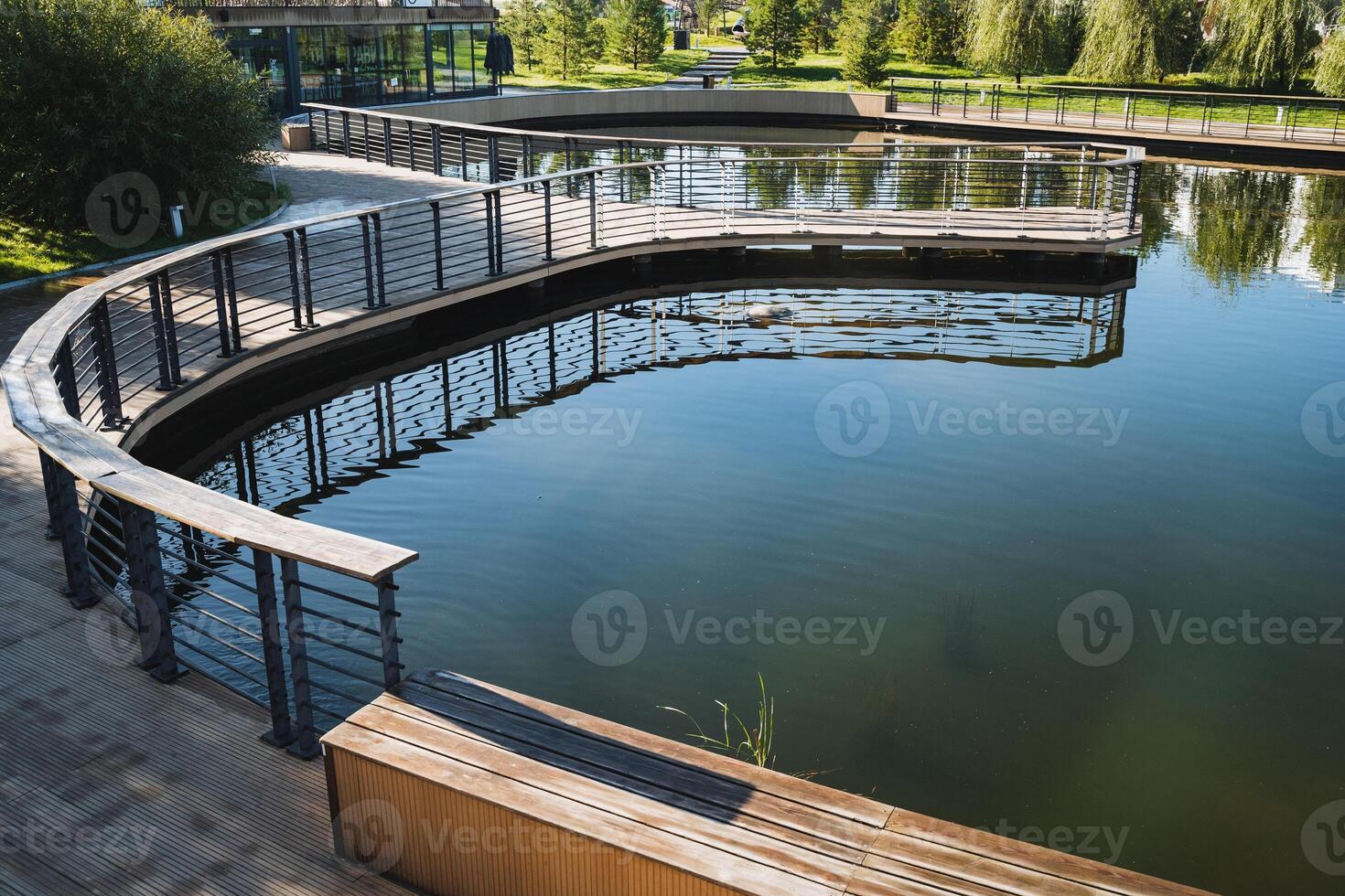 A picturesque bridge spanning across a tranquil lake located within a serene park, featuring a charming wooden bench positioned prominently in the foreground for relaxation photo
