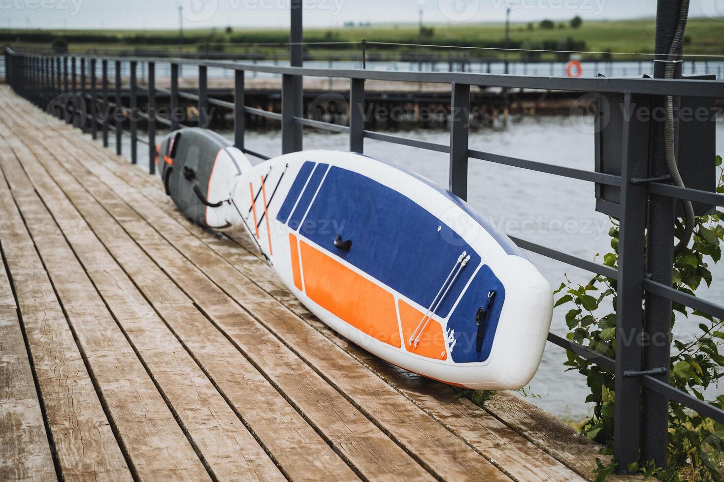 A surfboard lies on a wooden dock by the water, creating a serene spot to admire the sea and waves. This dock is ideal for savoring the beauty of the board and the surrounding nature photo