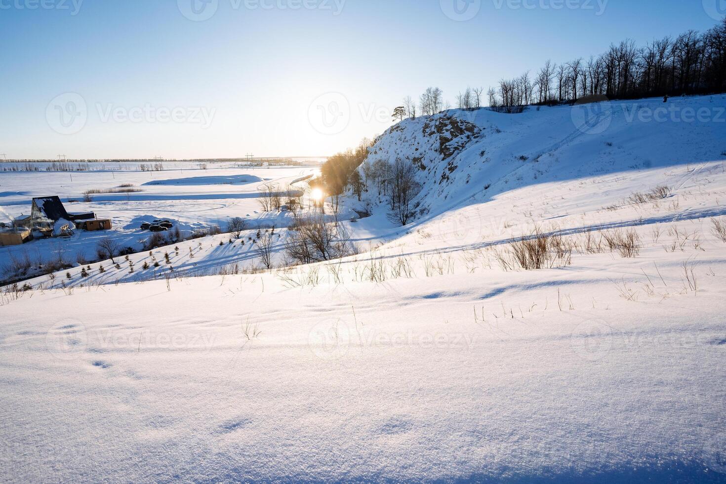 Beautiful winter landscape on the background of the mountain at sunset, the glare of the sun appeared behind the mountain, trekking in nature in the forest on the snow. photo