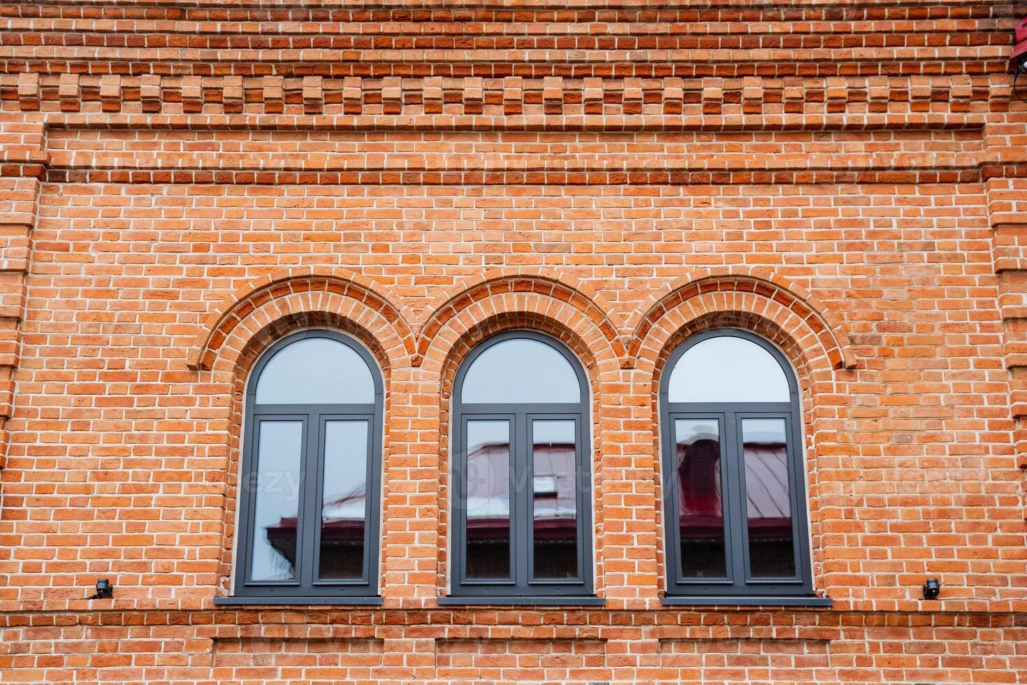 There is a brick building that features three elegant arched windows prominently displayed on one of its sides, adding charm and character to its overall aesthetic appeal photo