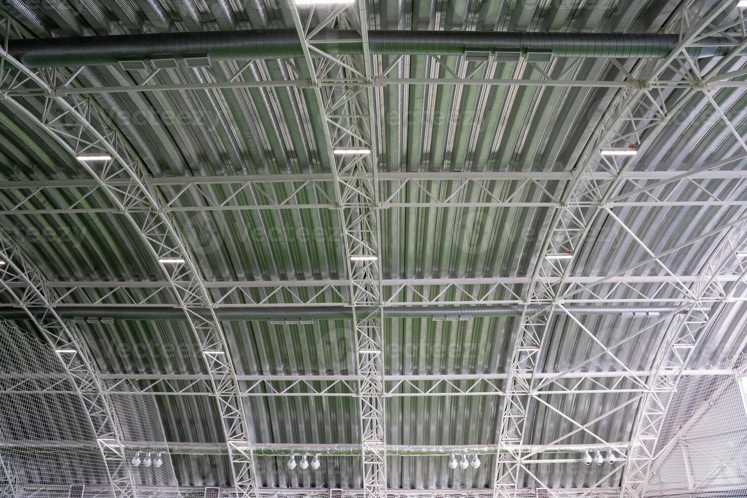 The buildings exceptionally spacious ceiling boasts intricate metal beams that contribute to a unique architectural design while effectively providing support for the entire roof structure photo
