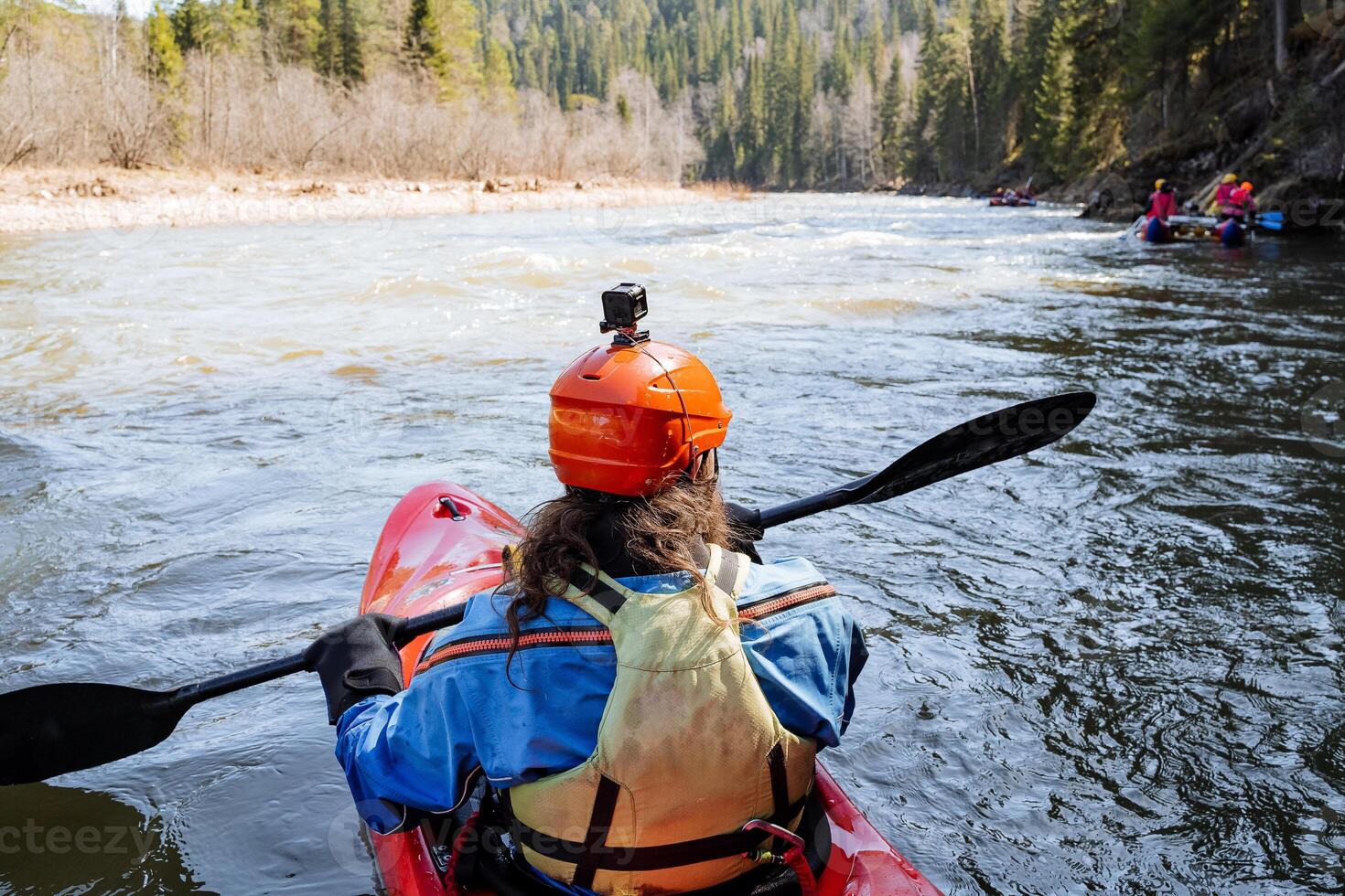 An experienced kayaker skillfully navigates a vibrant spring river, fully embracing and appreciating the breathtaking beauty of nature all around photo