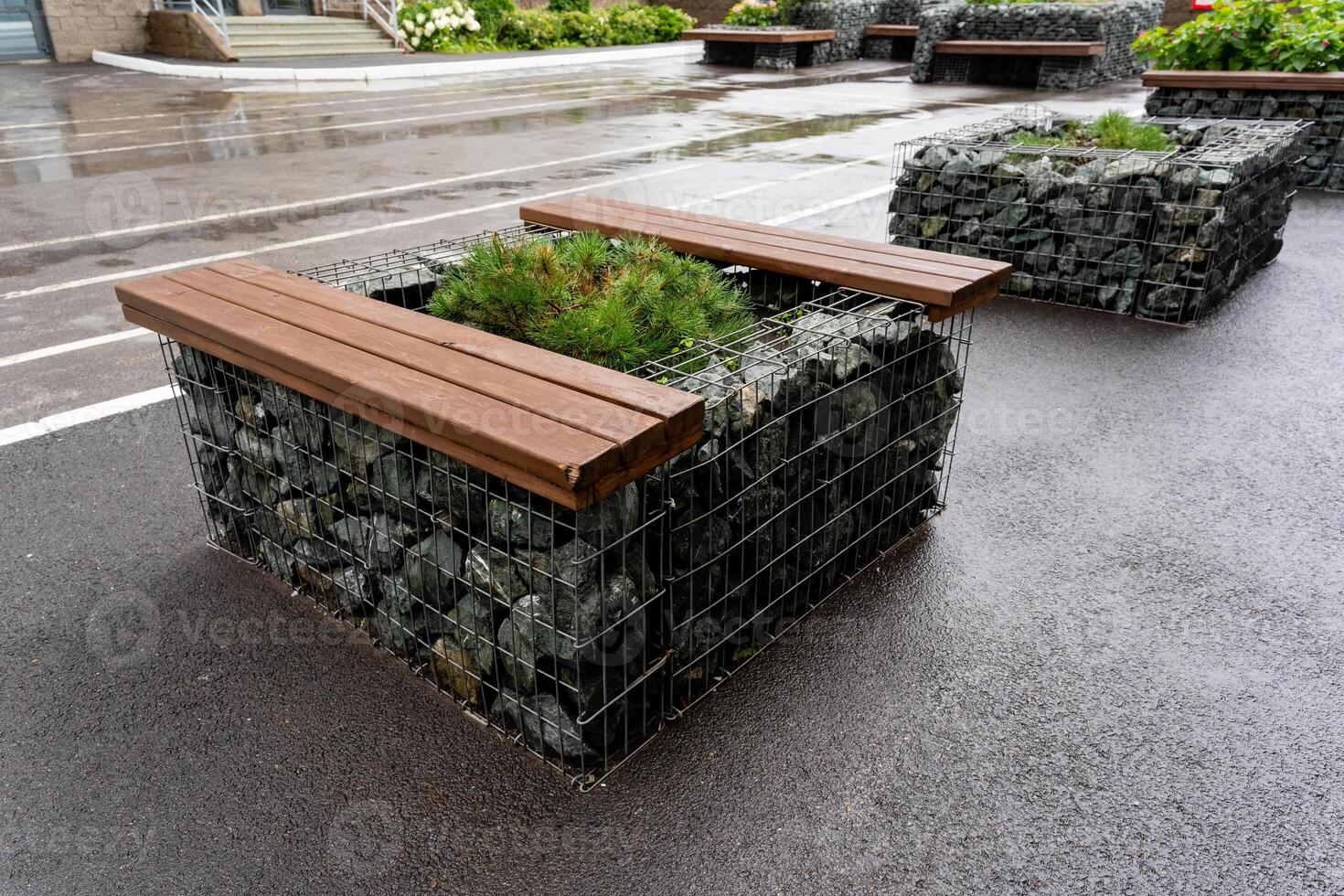 A wooden bench is positioned comfortably and securely atop a stone planter, creating a delightful combination of natural materials and practical urban seating for people to enjoy photo