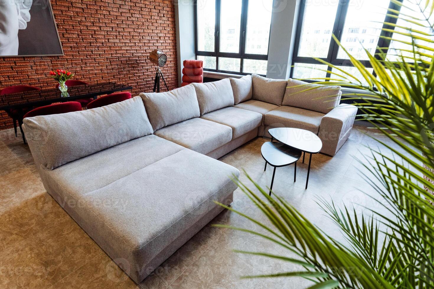 Aesthetically pleasing modern living room features a spacious Lshaped sofa and a stylish brick wall accent, creating a bold and contemporary space filled with natural light photo