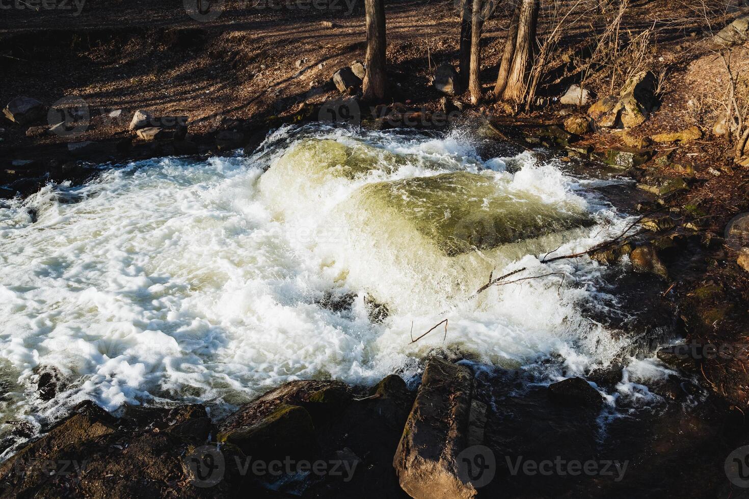 In the heart of the woods, a stunning waterfall cascades down, beautifully surrounded by an array of rocks and lush trees, creating a serene natural landscape that captivates all who visit photo