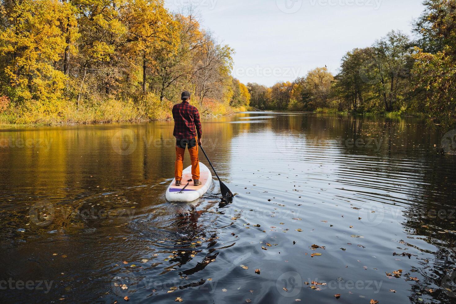Embark on a paddleboarding adventure during the beautiful autumn season, where serene reflections grace a calm river, creating a peaceful atmosphere photo