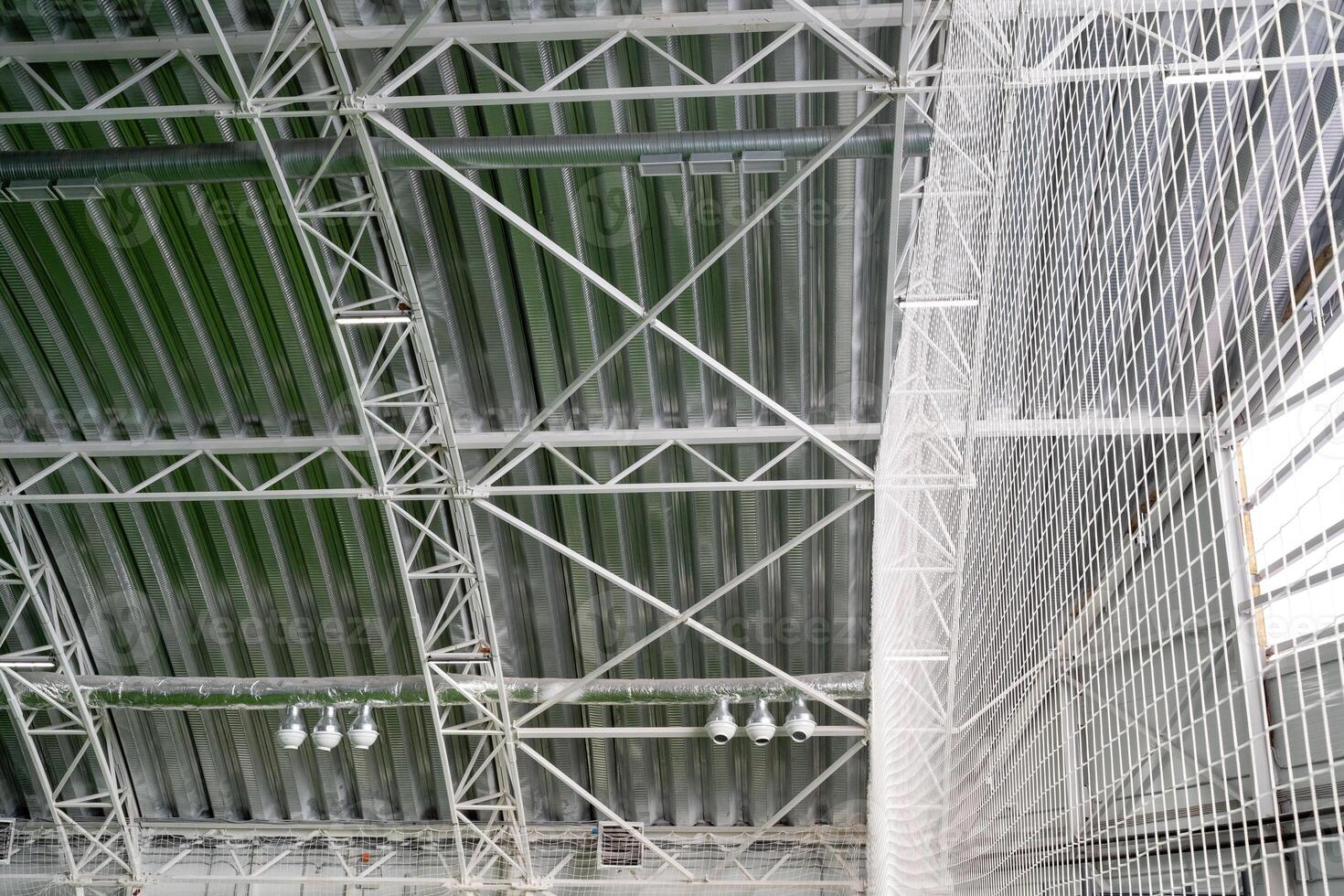 The buildings ceiling features an elaborate design with intricately arranged metal beams, providing structural support while creating a captivating aesthetic that draws attention photo