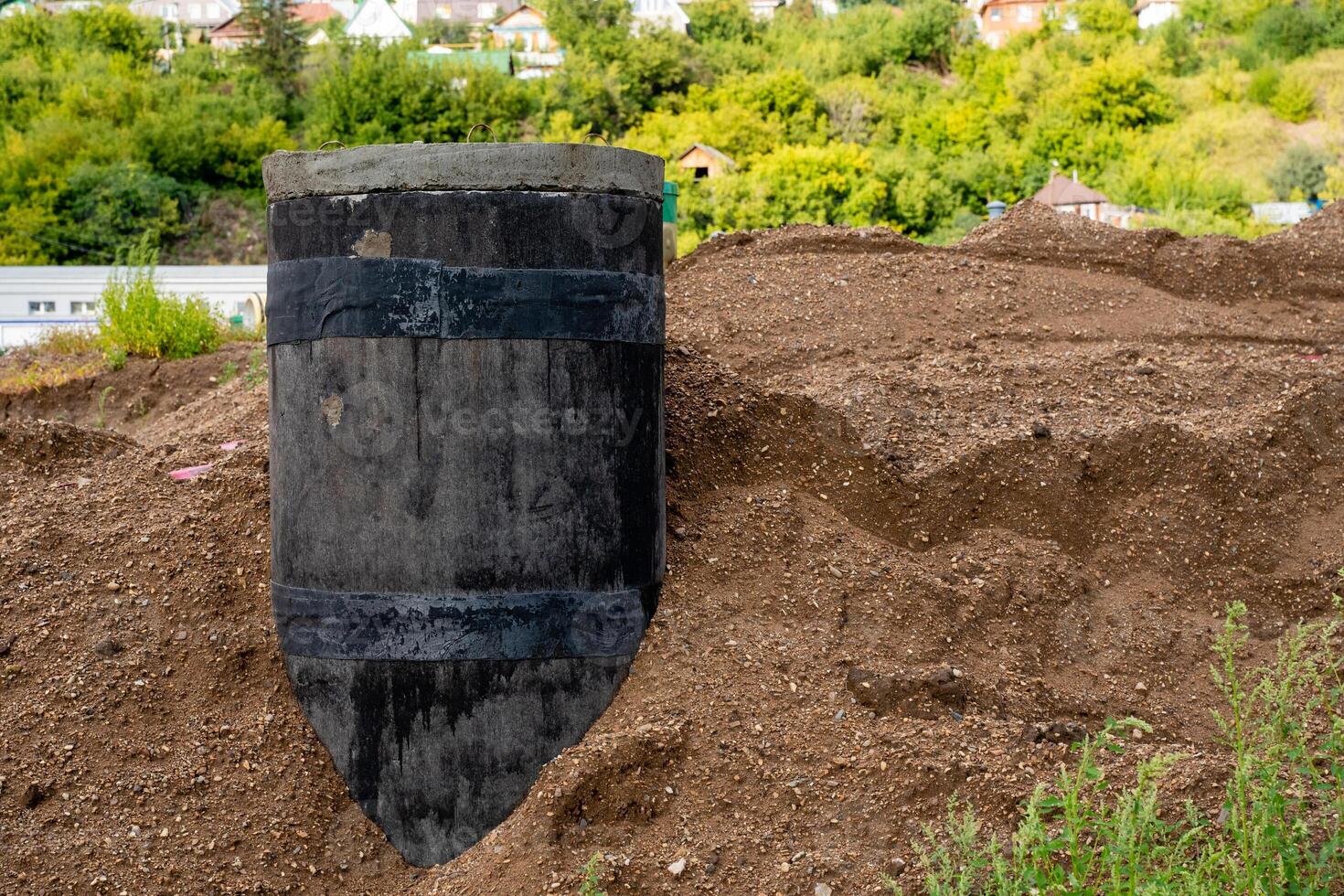 Excavated Black Structure Surrounded by Soil, Vegetation, and Various Natural Elements in the Landscape photo