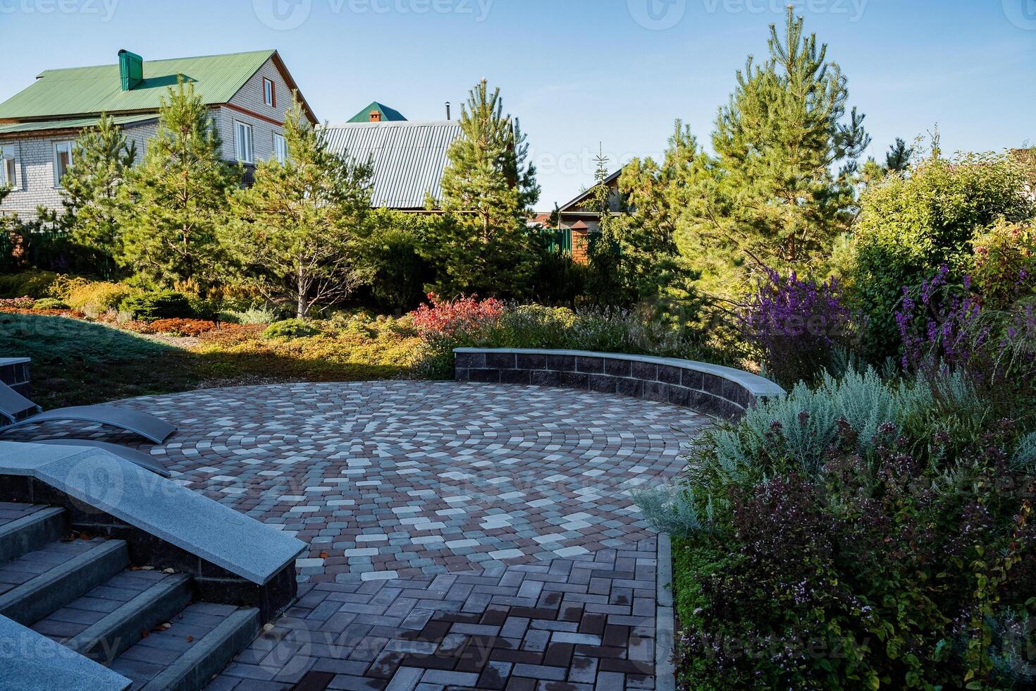In the background, a charming house complements a beautifully maintained brick walkway in the foreground, guiding the eye through the landscape and enhancing its aesthetic appeal photo