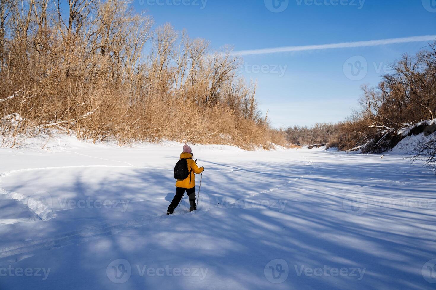A person in a yellow jacket walks on snowy slope under cloudy sky photo