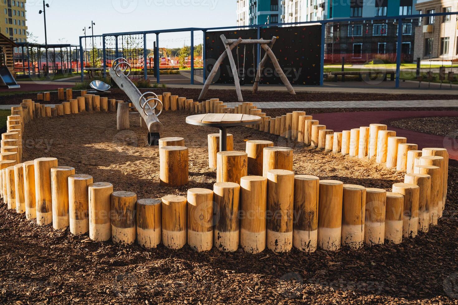 A playground featuring a fenced area constructed from sturdy logs and equipped with a table for various activities, creating a perfect space for children to play and socialize photo