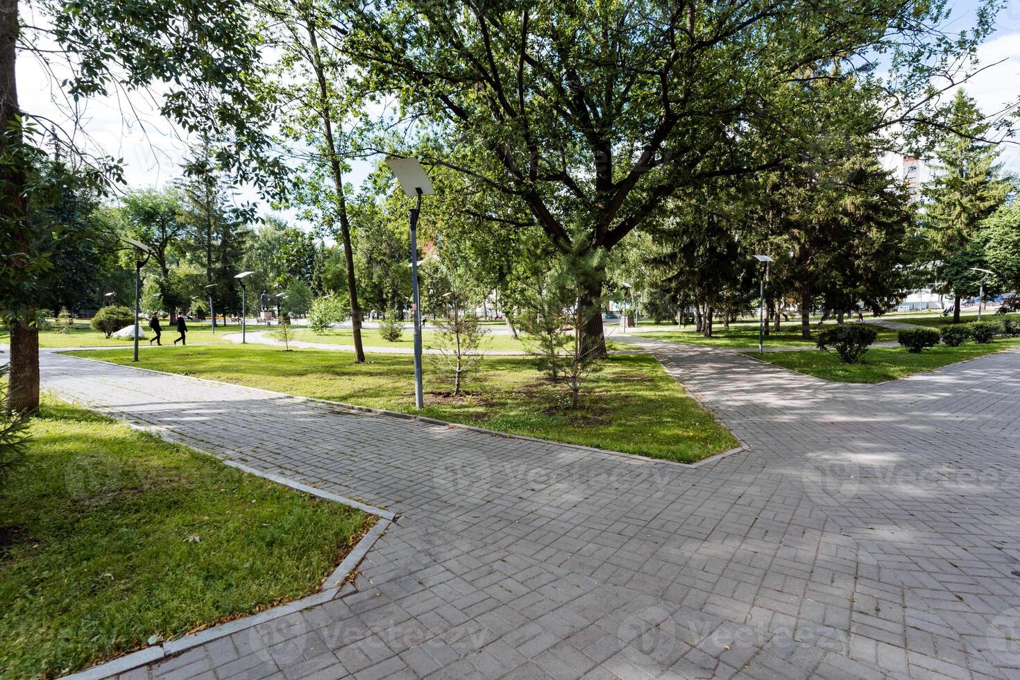 A peaceful natural landscape is created by a beautiful brick walkway in a serene park setting with lush trees and green grass. It offers a tranquil and serene environment photo