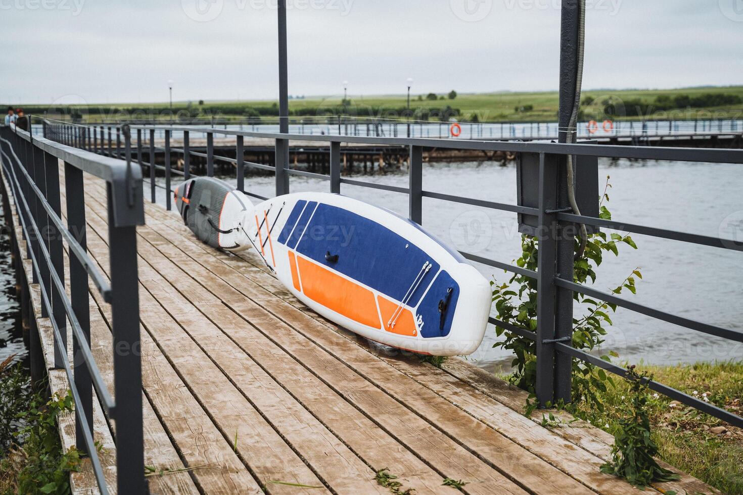 A peaceful wooden dock by a tranquil lake with a paddleboard symbolizes calmness and isolation in a remote, peaceful setting, perfect for relaxation and tranquility photo