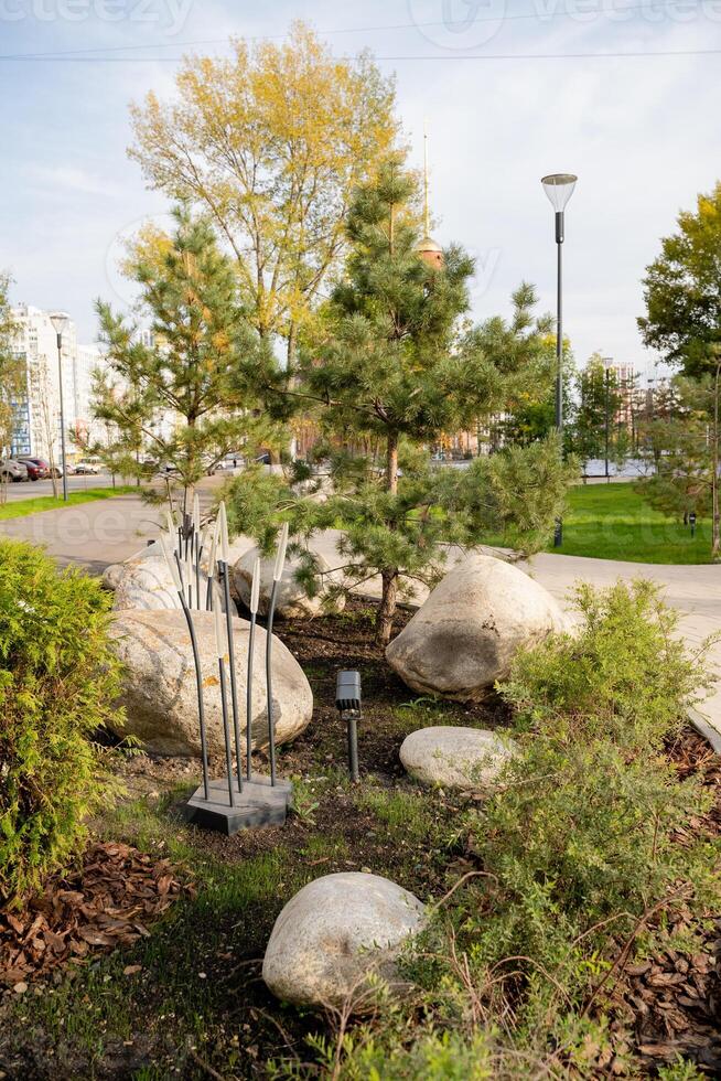 In the park, you can find numerous rocks and a diverse variety of trees, creating a vibrant and natural atmosphere for visitors to enjoy and explore the beauty of nature photo