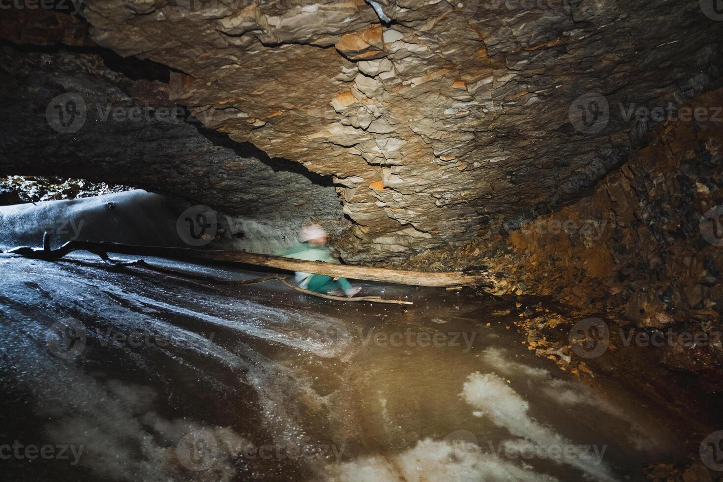 In a dimly lit cave, a person stands firmly grasping a sturdy wooden stick, indicating they might be exploring or preparing for an adventure within the caves mysterious depths photo