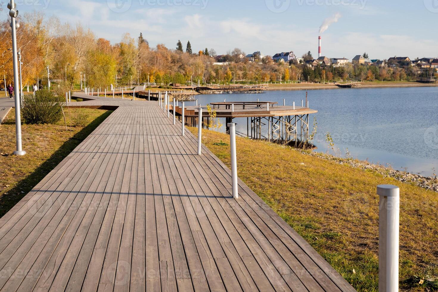 A scenic wooden walkway gracefully leads the viewer toward a tranquil body of water, inviting exploration and reflection amid the beauty of nature and its natural landscape photo