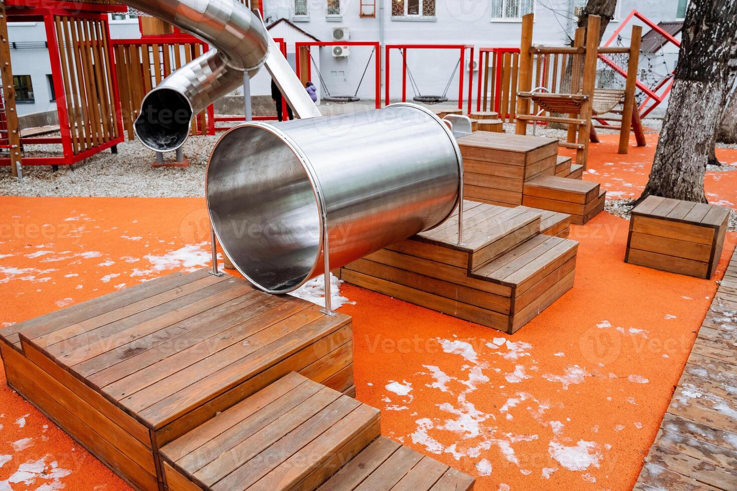 A shiny and durable stainless steel slide is gracefully going down the wooden steps located in a fun and exciting playground, inviting children to enjoy their playtime experience photo