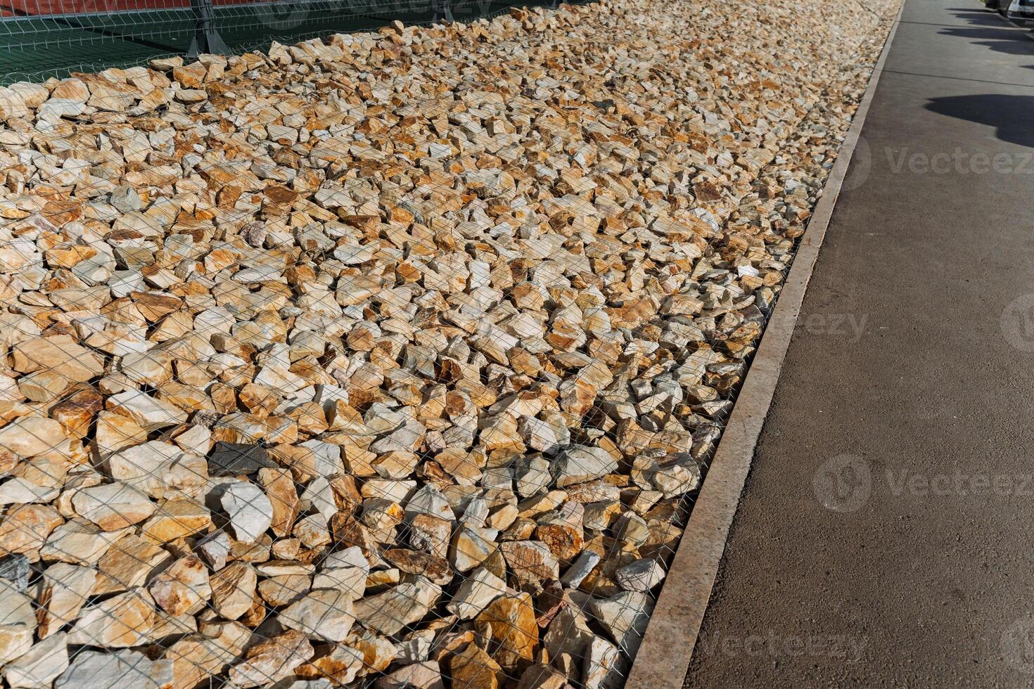 A sizable pile of gravel is currently sitting on the side of a road, possibly waiting to be used for construction or repairs in the nearby area or for a road surface project photo