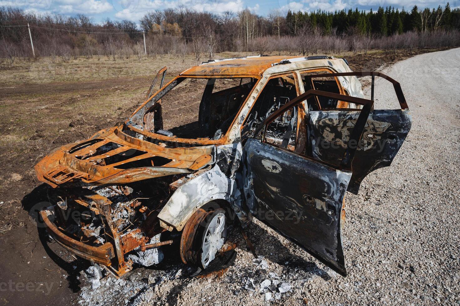 A vehicle was fired upon, a car burned to the ground on the side of the road, a rusty car body was thrown into a field. photo