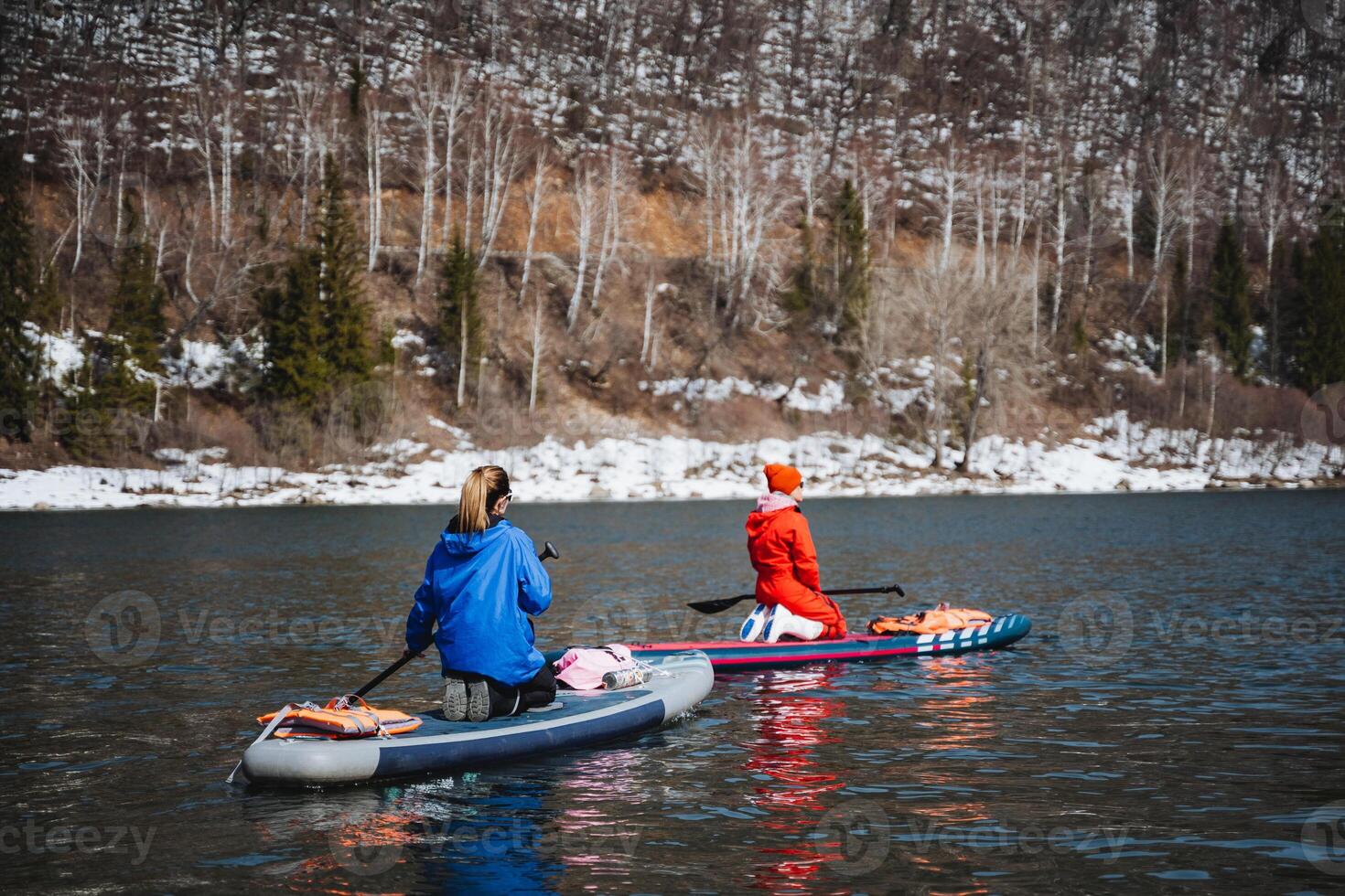 Women float on a SUP board on the river against the background of mountains, rowers with a paddle on a board, tourists sail on the lake, outdoor recreation. photo