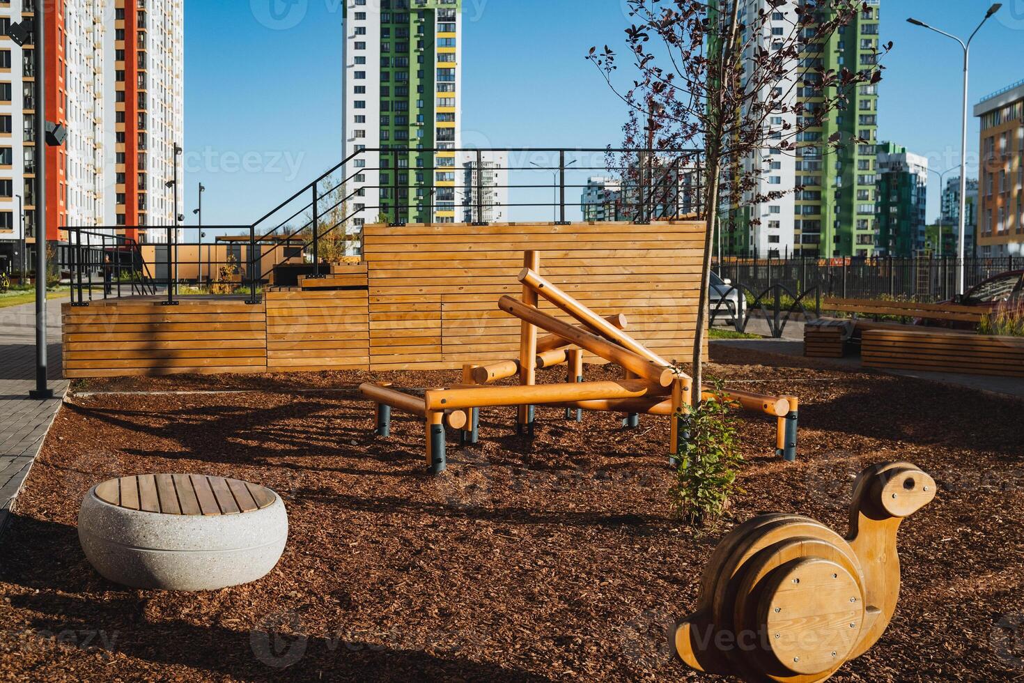 In the center of an expansive playground, a charming wooden snail is perched, offering a delightful touch of whimsy to the scene, surrounded by children and play equipment photo