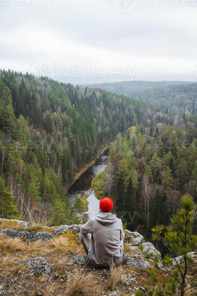 Contemplative Moment A Thoughtful Individual Wearing a Red Hat Contemplatively Overlooking a Serene and Peaceful Forest Landscape photo