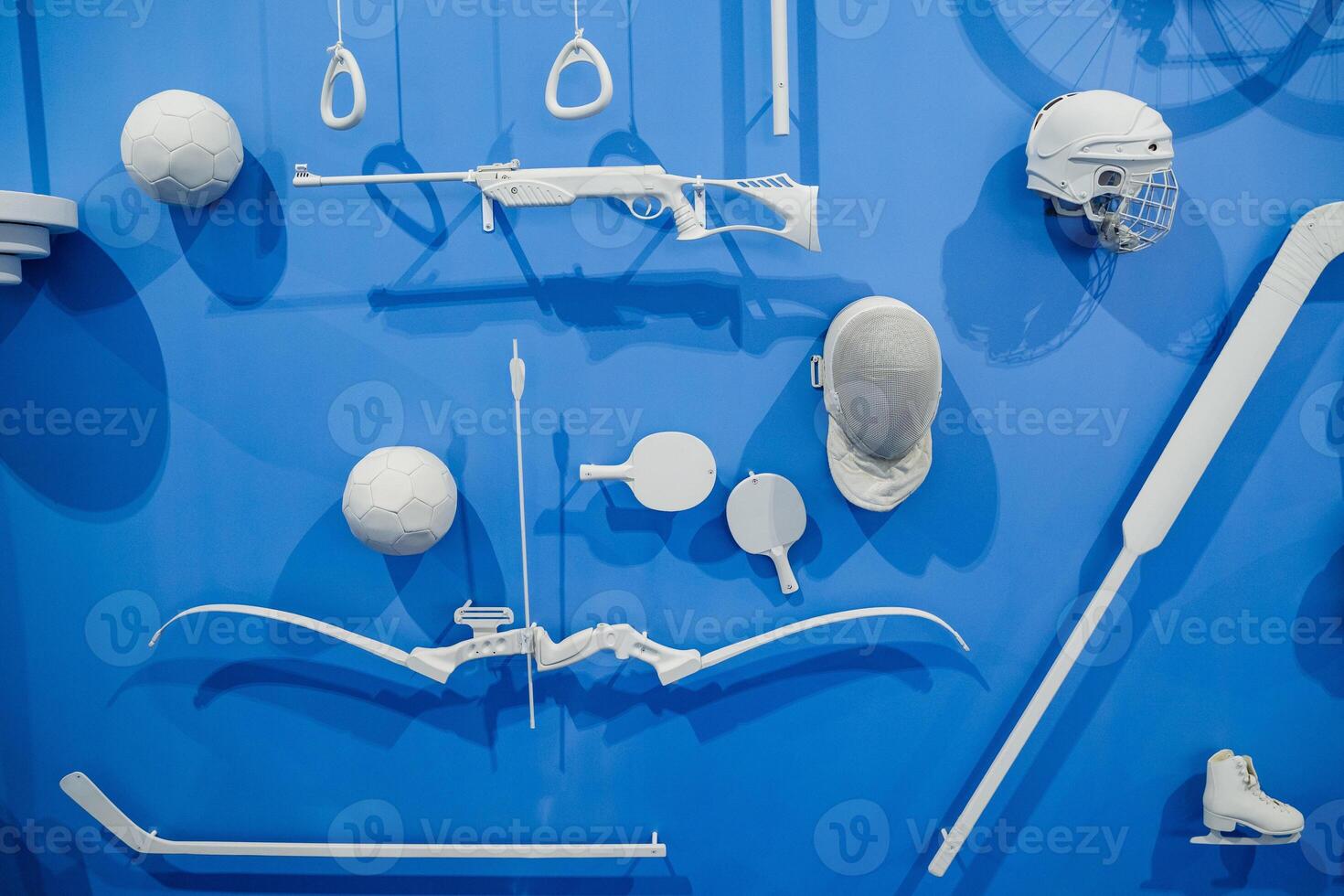 The scene features a blue wall adorned with a variety of white sports equipment that is hanging or displayed on it, creating a striking contrast in colors and showcasing multiple items photo