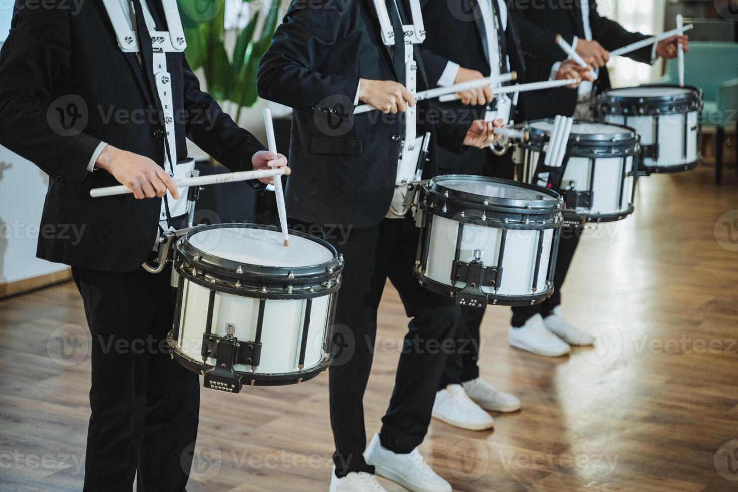 Men in suits playing drums in a marching band with percussion mallets photo