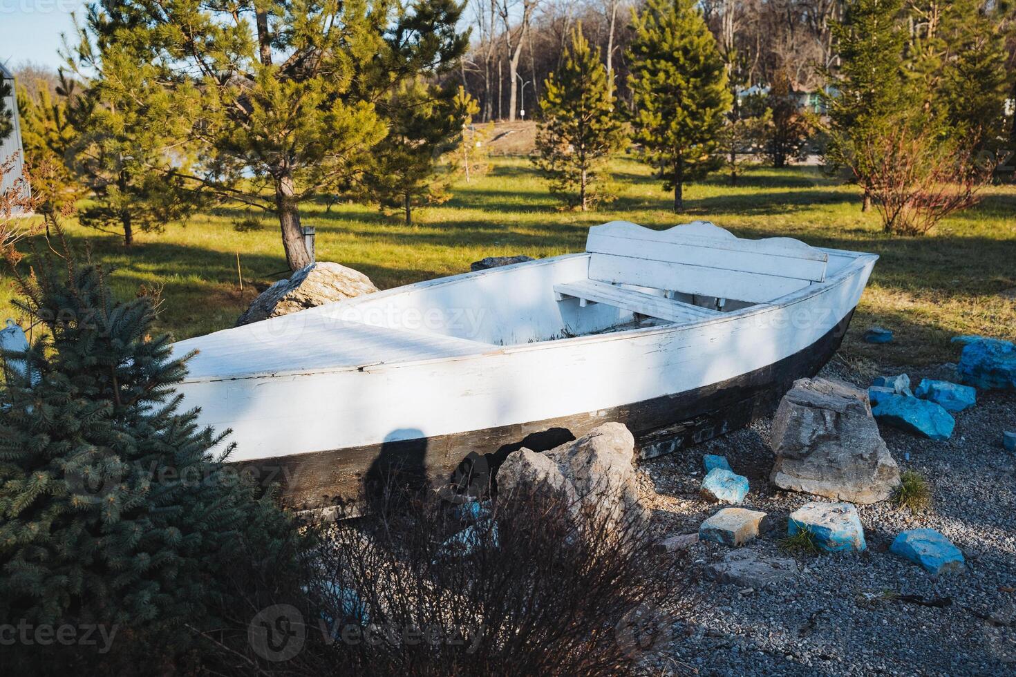 In a beautiful park, a white boat is gracefully resting on the ground, creating a striking contrast against the vibrant greenery and the natural landscapes surrounding it photo