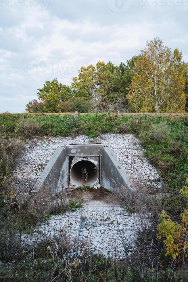 In the very center of a vast and open field, a large industrial pipe meanders its way through a rugged and rocky area, creating an intriguing contrast to the surrounding natural landscape photo