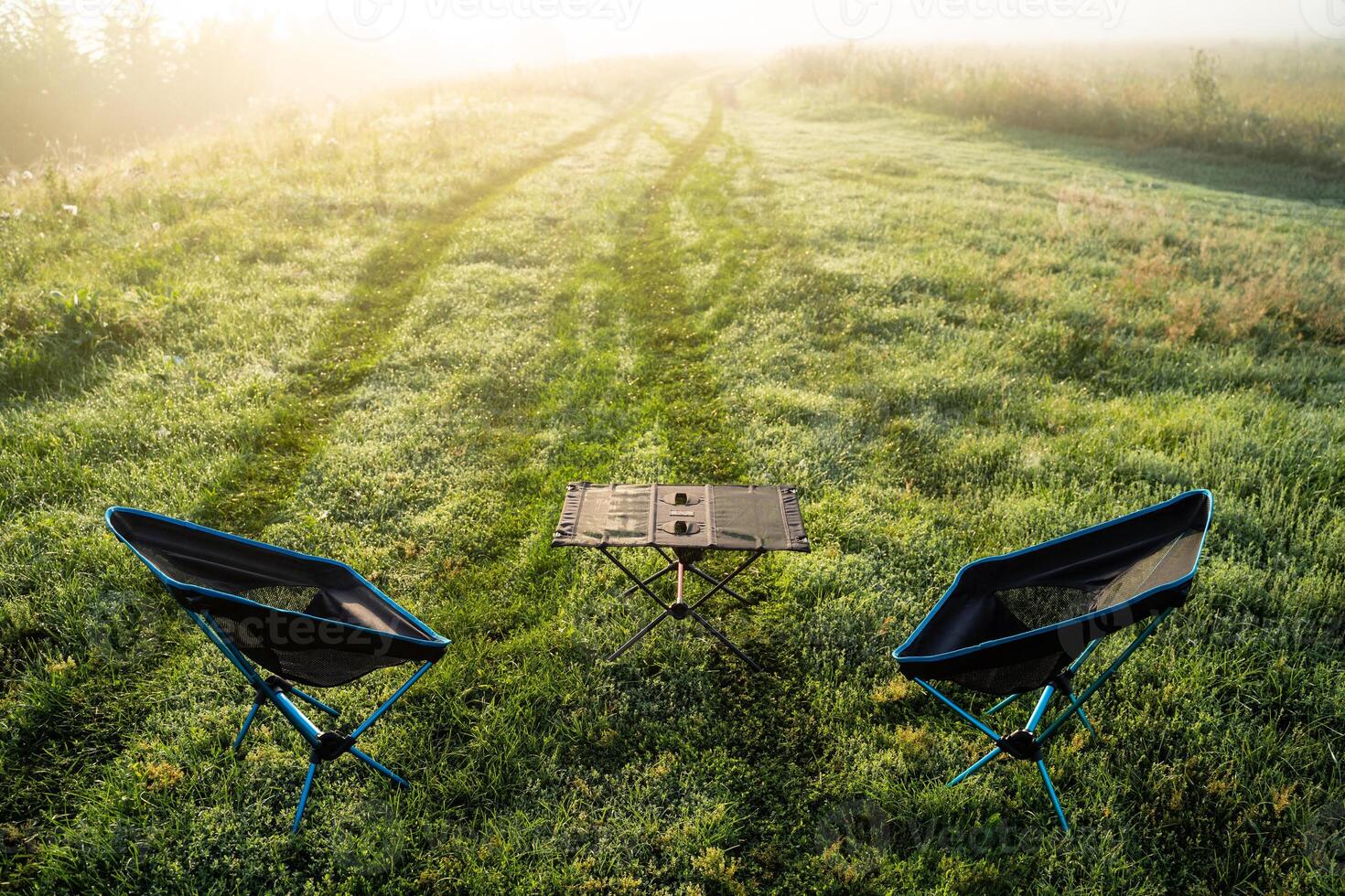 A Serene and Inviting Morning Picnic Setup in the Embrace of Nature with Comfortable Chairs and a Table photo