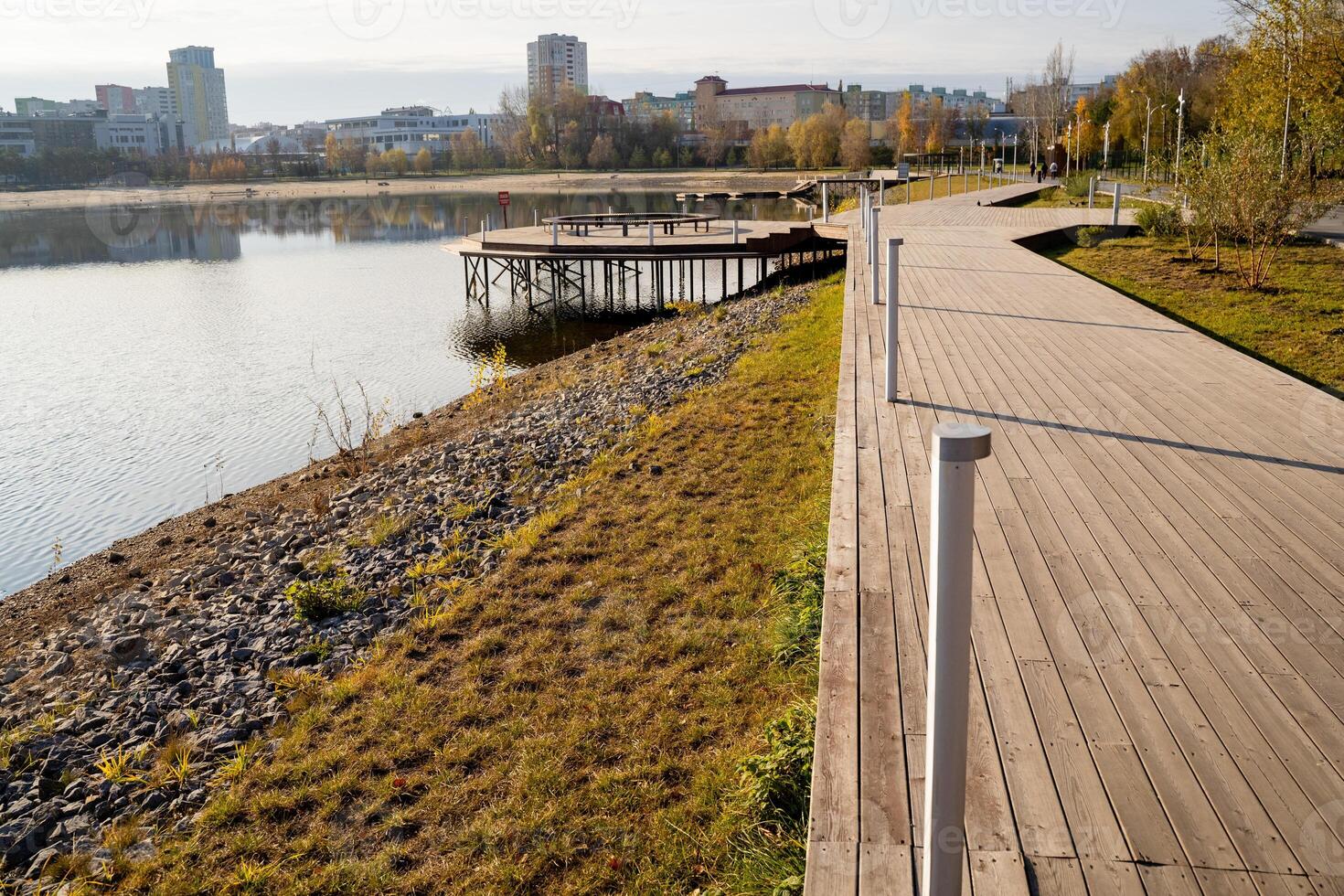 A wooden walkway leading to a lake with a dock in the background photo