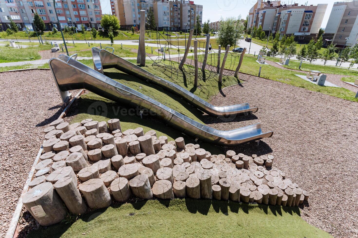 The park features a distinctive play area combining a metal slide and wooden logs, creating a harmonious urban design fusion of metal, wood, and nature. Its an artistic blend of elements photo