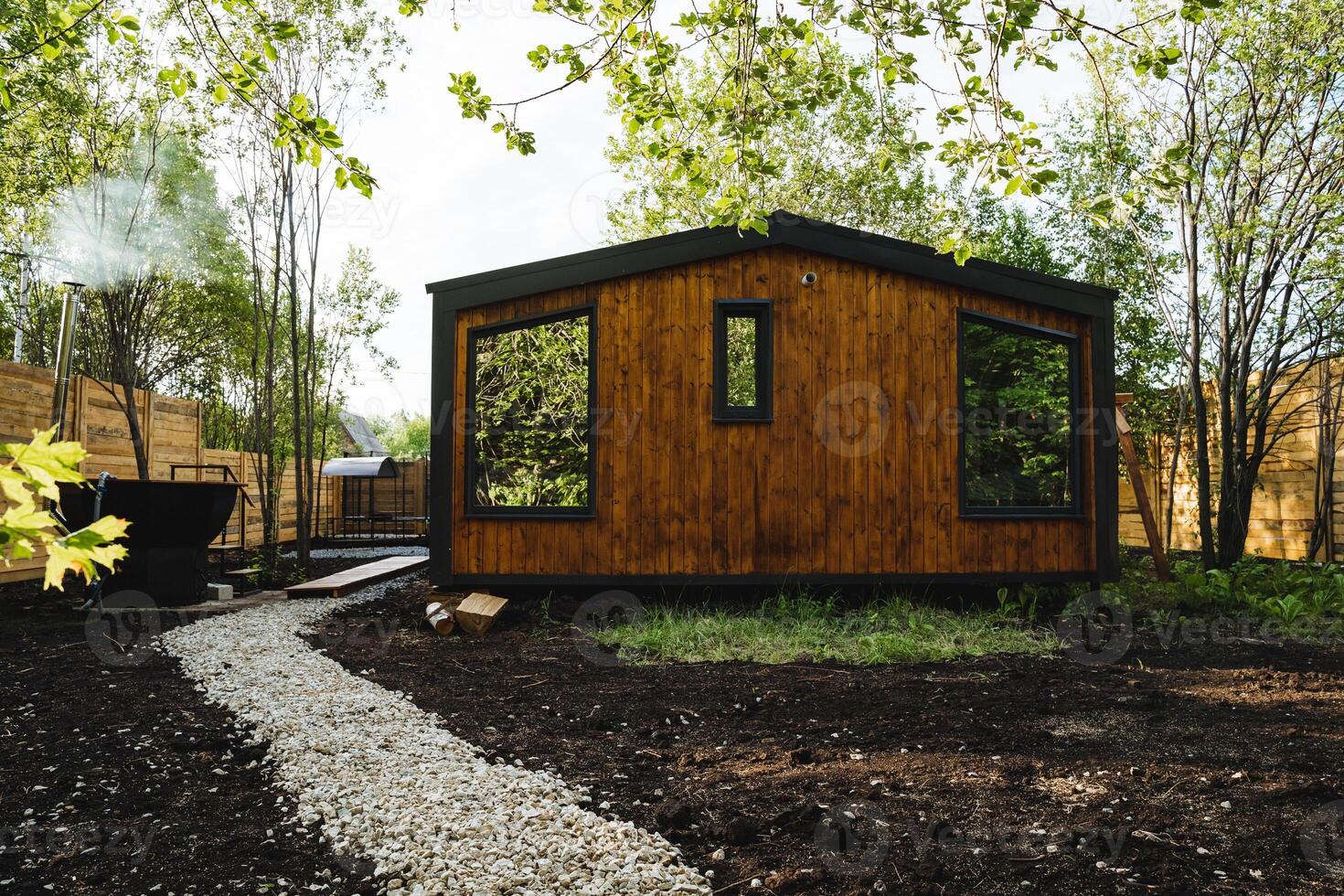 Nestled among the trees is a charming wooden cottage, blending perfectly into the natural surroundings. Its numerous windows create a tranquil and soothing environment, ideal for relaxation photo