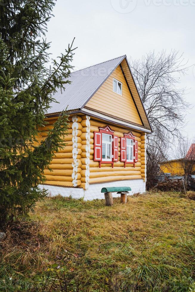 A charming yellow wooden cottage, beautifully surrounded by lush nature, offers a serene and tranquil escape in the picturesque countryside photo