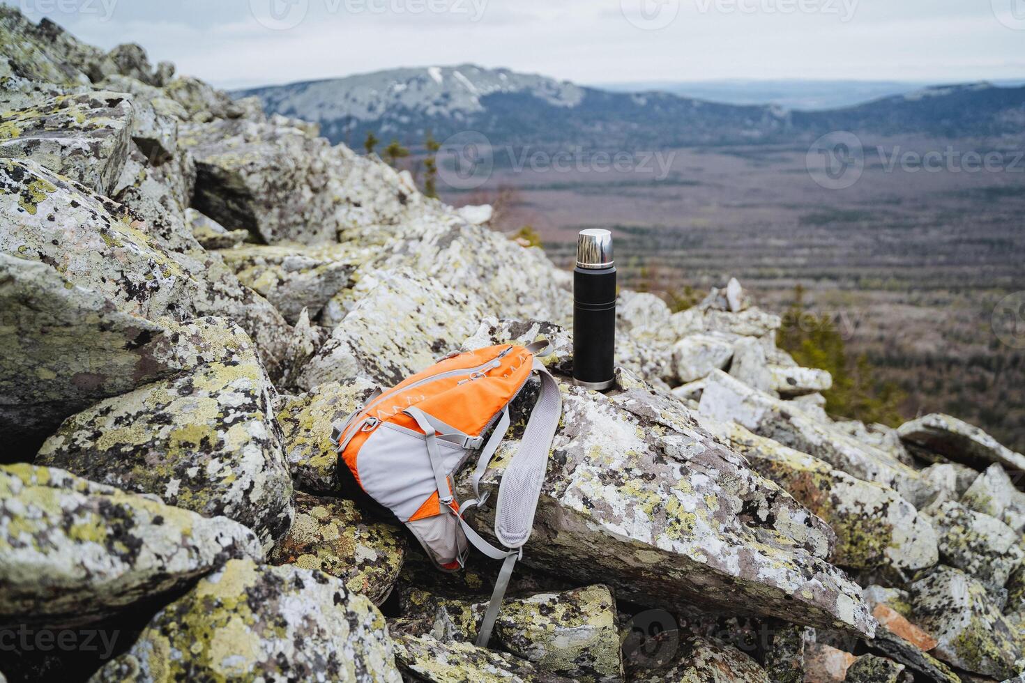 Hiking to a rocky mountain summit with backpack and thermos, enjoying a scenic view of expansive landscape. Adventure in untouched nature, high altitude escapism photo