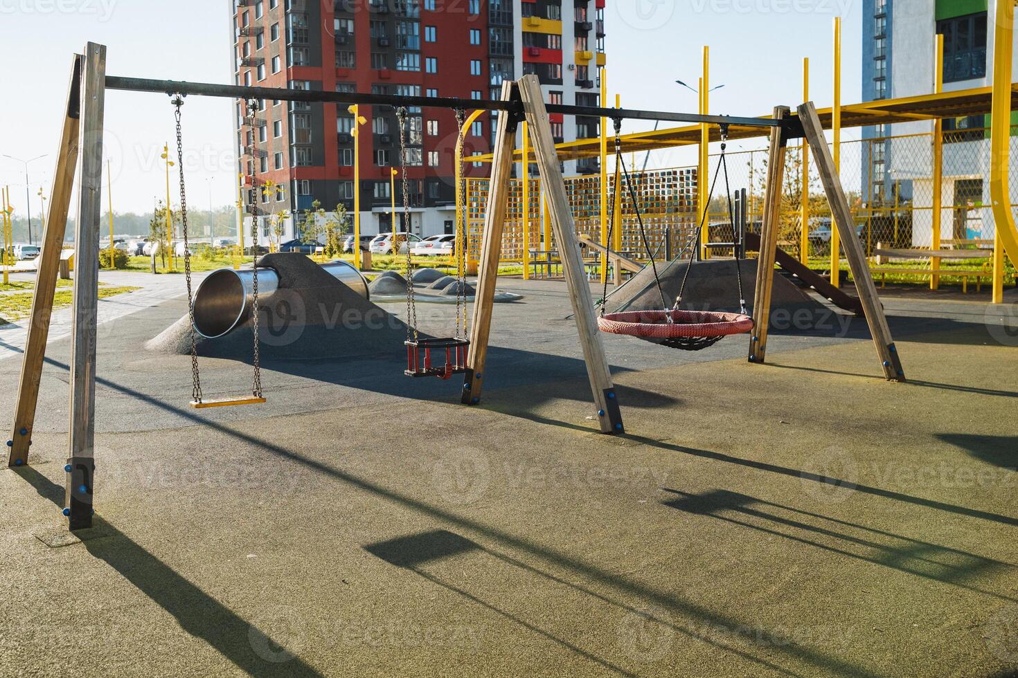 In the distance, there is an empty playground, a space where children often gather to joyfully play, situated directly in front of a building, contributing to a beautiful urban scene photo