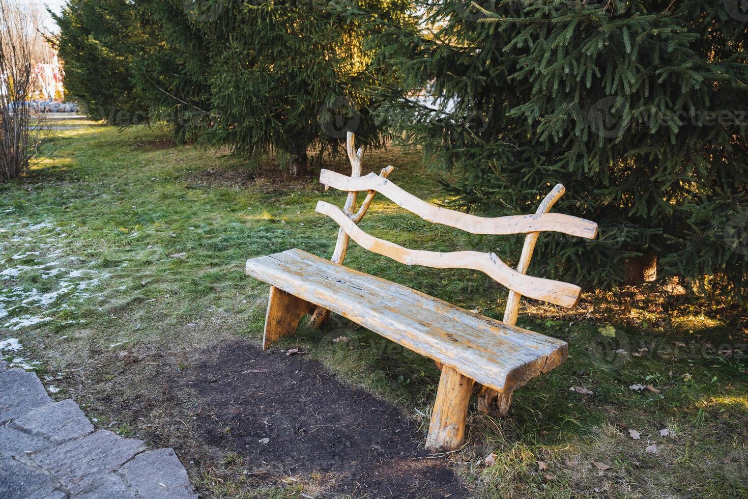 A beautifully crafted wooden bench sits gracefully in the lush, vibrant grass of a scenic park, warmly inviting visitors to come, sit, and fully enjoy the peaceful natural surroundings photo