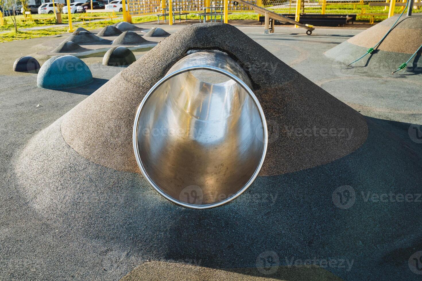 A metal pipe is going down a hill in a playground photo