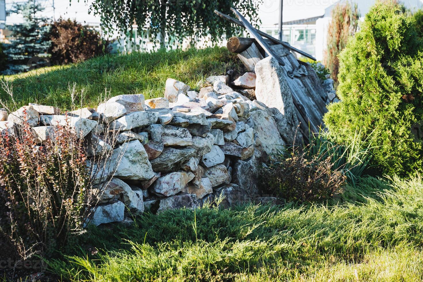 In a beautifully lush grassy field, there exists a notable pile of assorted rocks that creates a striking and eyecatching contrast with the vibrant green surroundings all around it photo